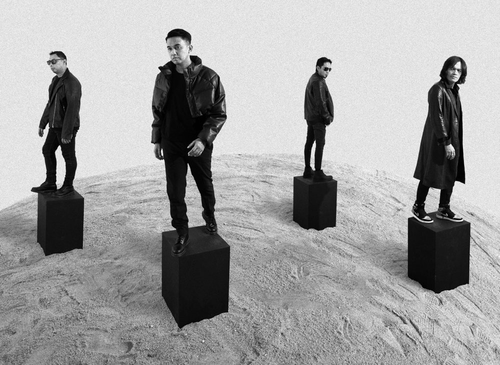 ADA Band standing on black plinths on a sand dune, black and white